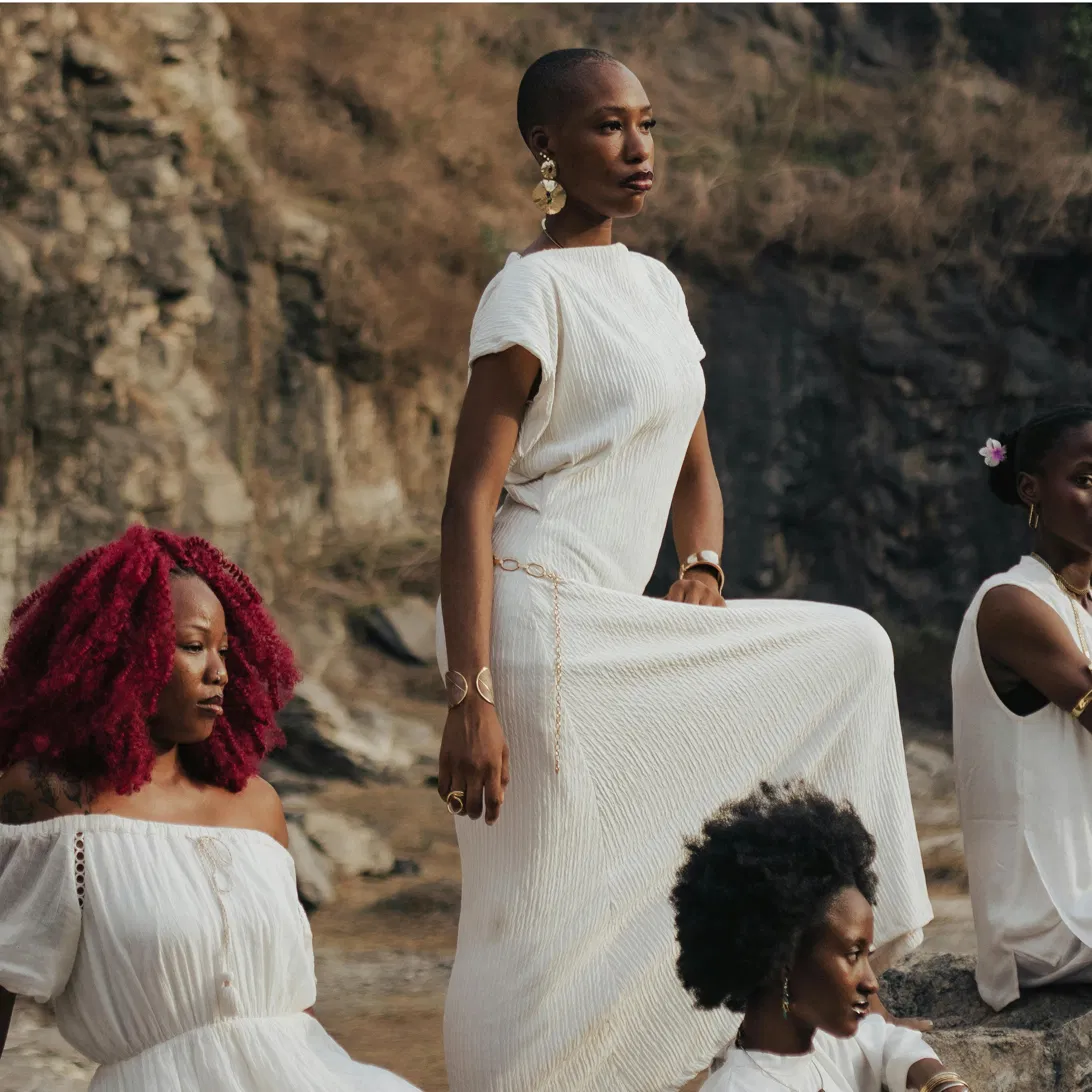 Black women standing together in white, outdoors