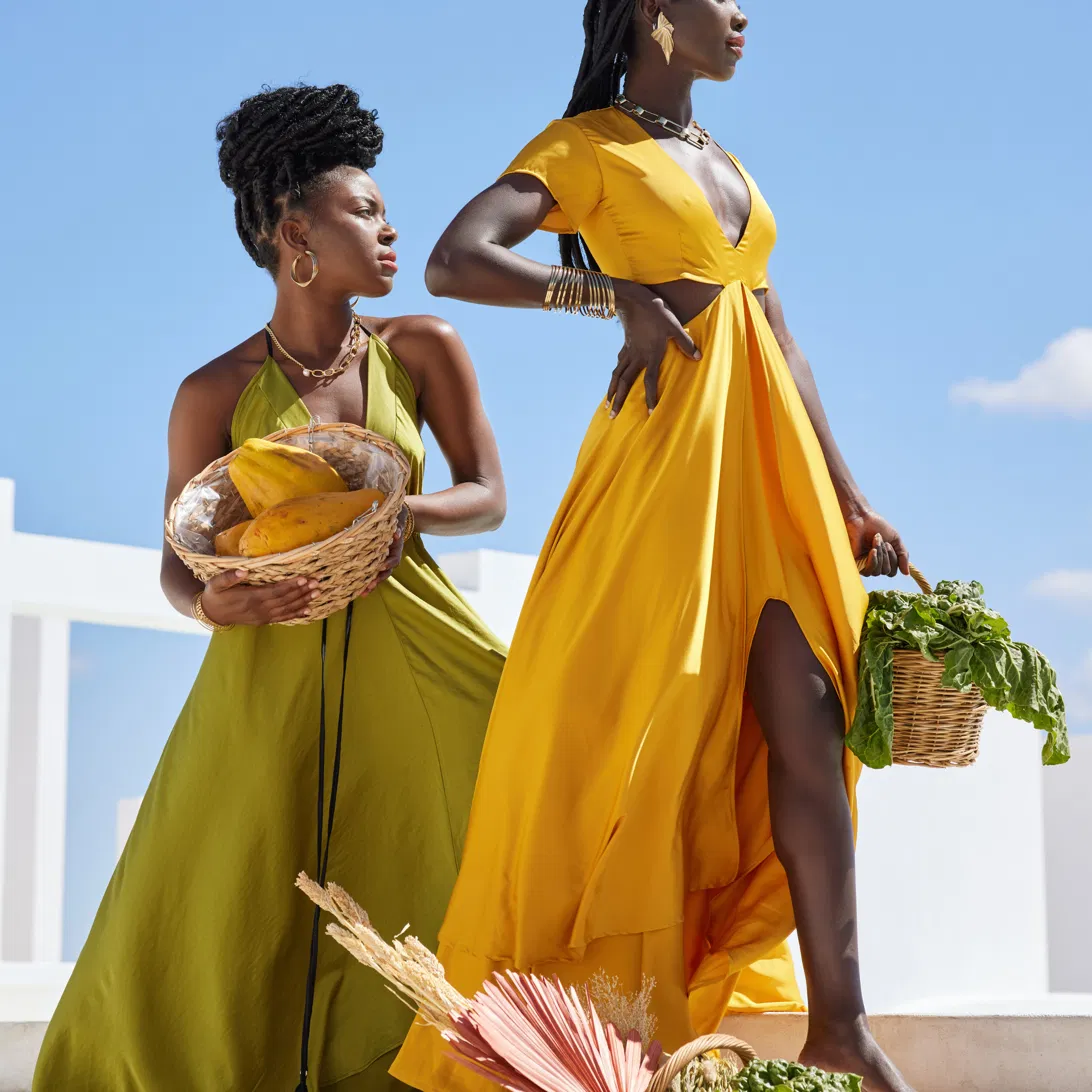 Two Black women in golden light holding baskets of fresh produce
